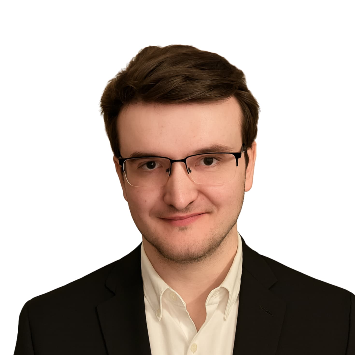 Portrait of a young man with brown hair, glasses, wearing a white shirt and black blazer, smiling at the camera against a white background.